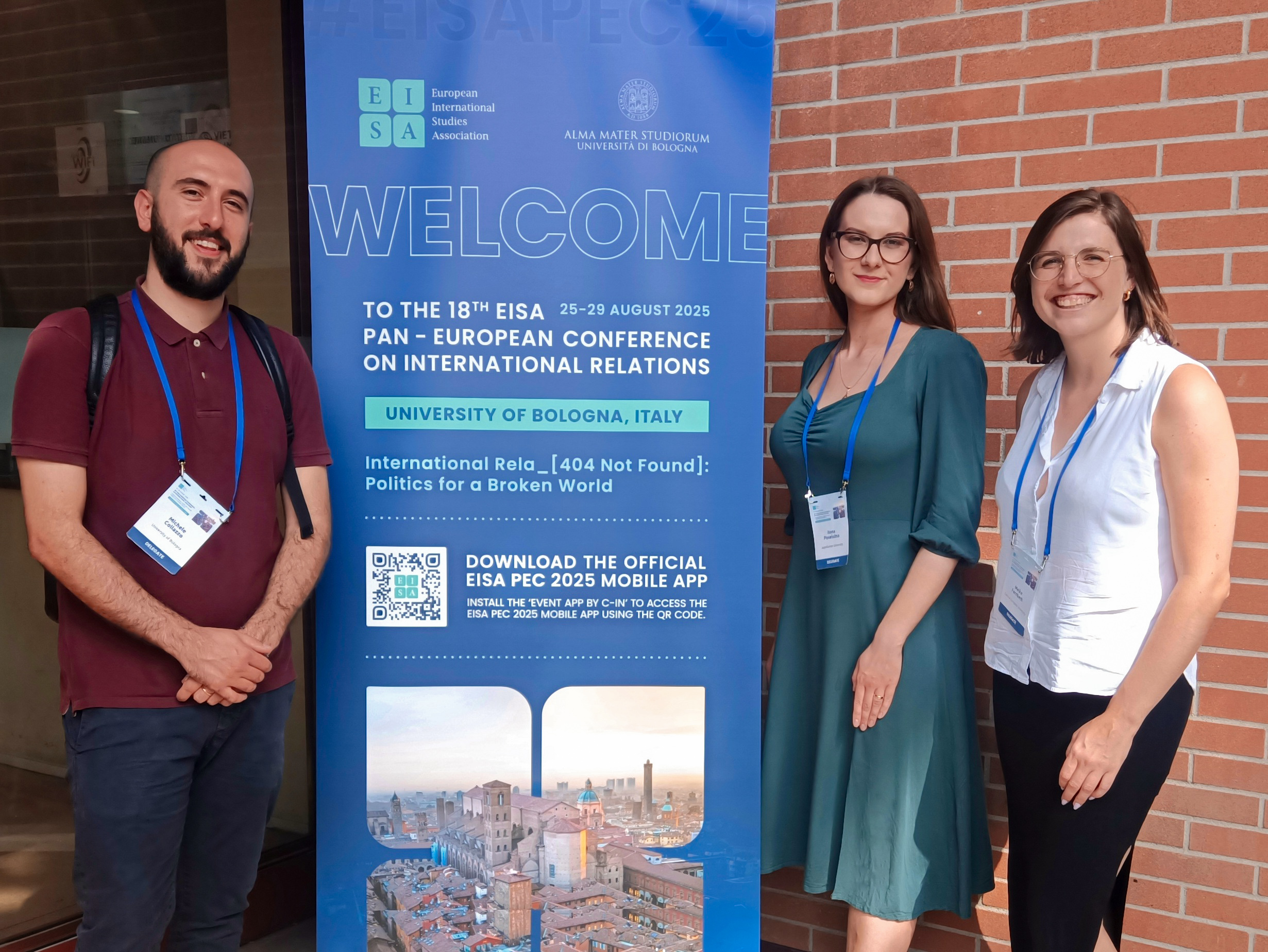 Three of the Scholars - Ilona, Michele and Meike - standing in front of a conference Welcome poster.