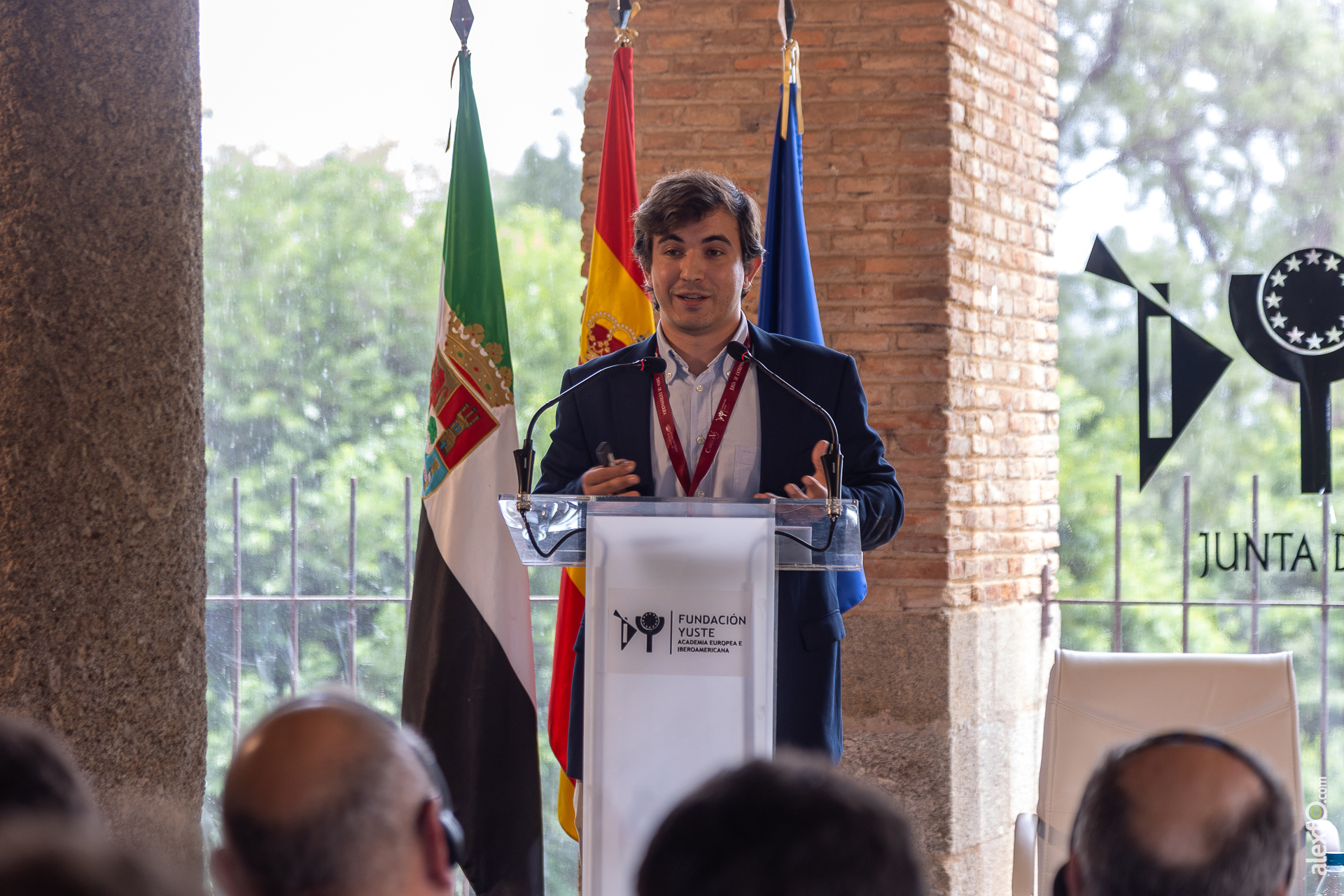 Amós Del Castillo Petidier (UCM) presenting at a podium in front of three flags